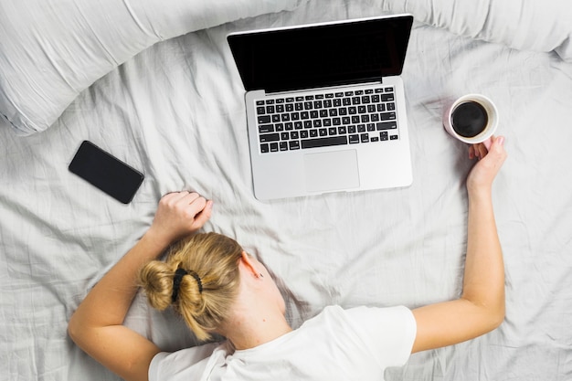 Woman sleeping on bed with laptop 