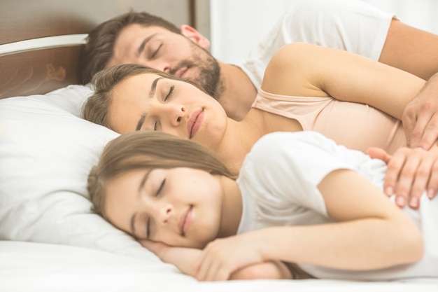 The woman sleeping near the family on the comfortable bed