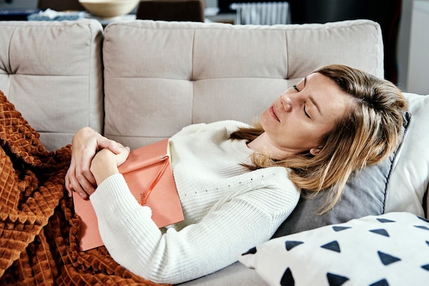 Woman sleeps on couch with book