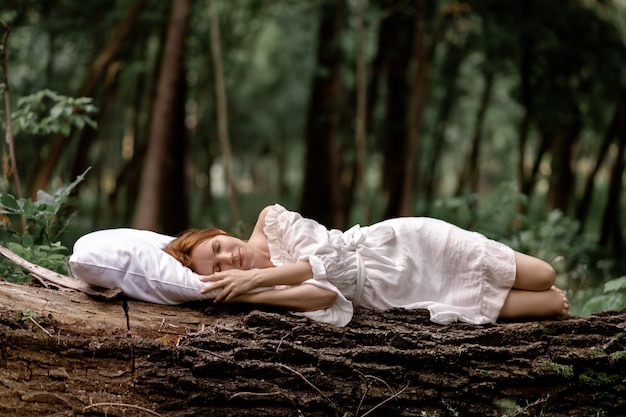 A woman sleeps in the woods on a pillow