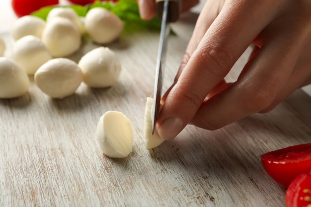 Woman slicing mozzarella on cutting board, close up