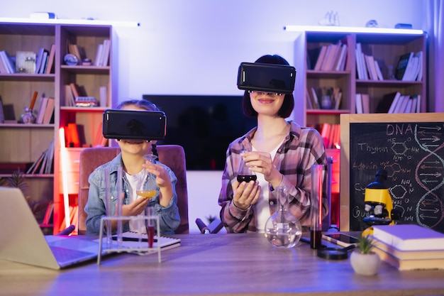 Woman and small kid girl improving knowledge using vr glasses at evening home