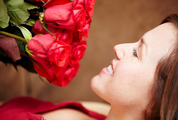 Woman smell roses and smile for valentines day gift present and celebration of love floral fragrance and bouquet Happy female person face and red flowers of plants in bloom blossom and perfume