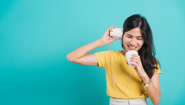 Woman smile white teeth standing wear yellow t-shirt, She holding paper can telephone