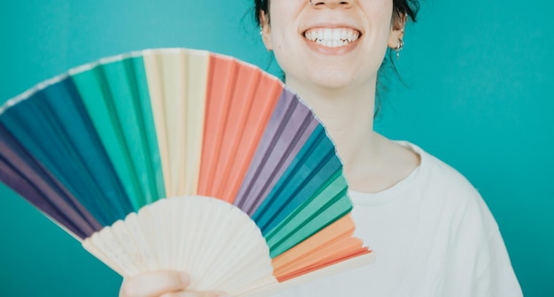 Woman smiling happily to camera while holding a LGBTIQ hand fan her showing pride Lesbian woman pride and fighting for her rights Love is love concept Color background image