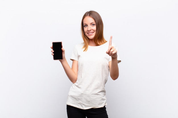 woman smiling and looking friendly, showing number one or first with hand forward, counting down