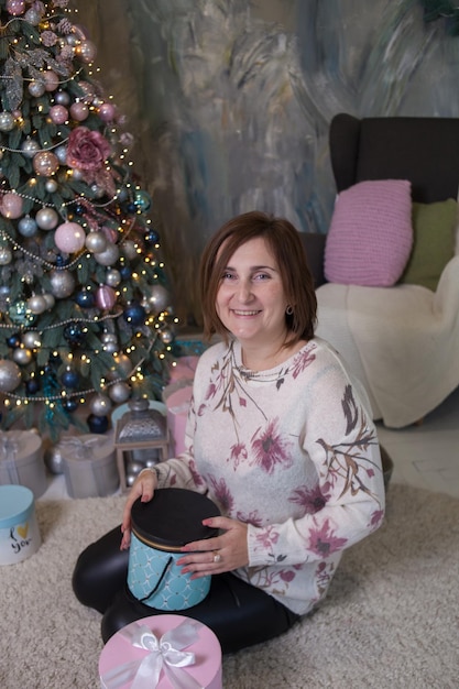 Woman smiling near christmas tree and holding a present