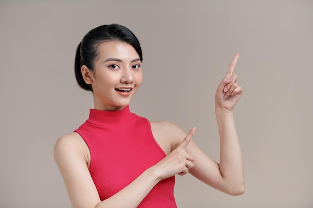 woman smiling and pointing fingers at copyspace isolated over white background