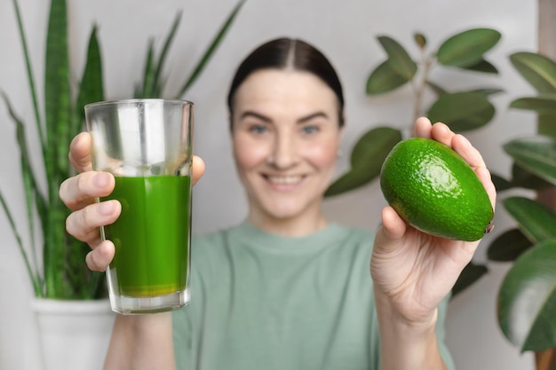 Woman smiling and shows green wheatgrass drink and avocado Healthy lifestyle concept green healthy vegetables and fruits