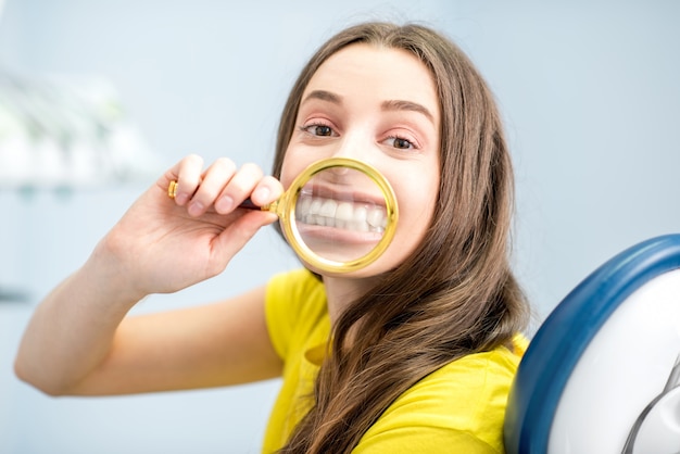 Woman smiling through the magnifying glass sitting at the dental office