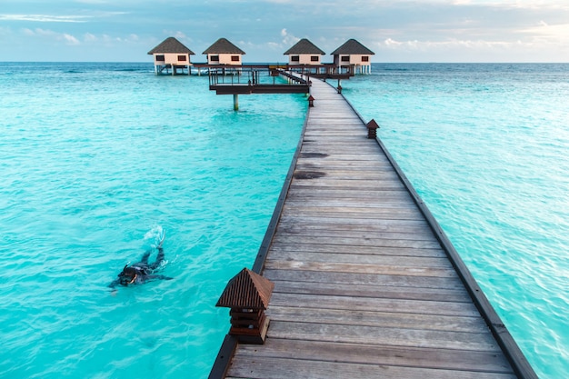 Woman snorkeling over crystal clear water at water villa