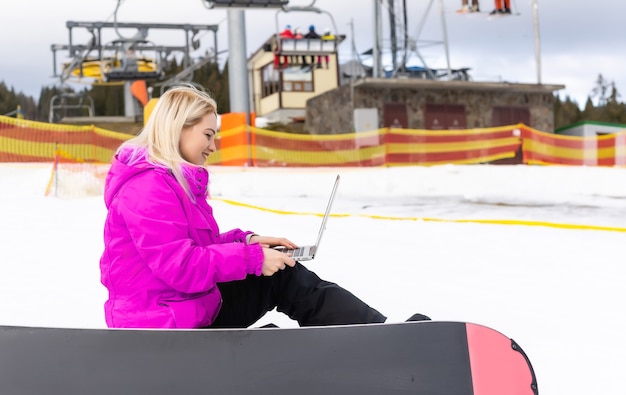 woman snowboarder working laptop in winter mountains