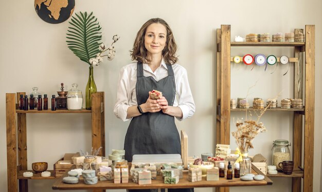 Woman soap maker in a workshop holds piece of fragrant natural soap in her hands