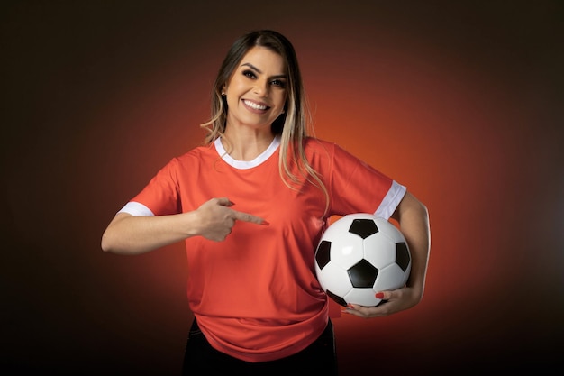 Woman soccer fan cheering for her favorite club and team world cup orange background