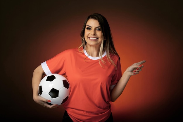 Woman soccer fan cheering for her favorite club and team world cup orange background