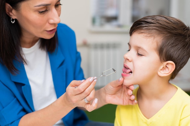 Woman speech therapist helps a child correct the violation of his speech in her office