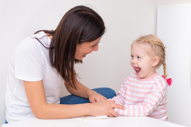 Woman speech therapist helps cute girl to learn correct pronunciation and competent speech in her office