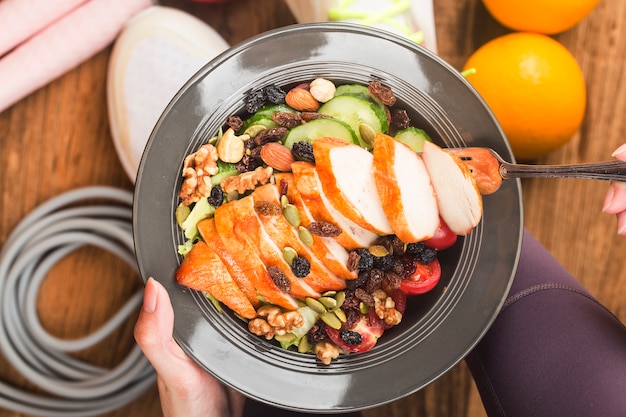 Woman in sport wear holding a dish of fresh salad