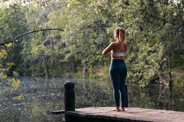 Photo woman in sportswear doing yoga outdoors near a lake