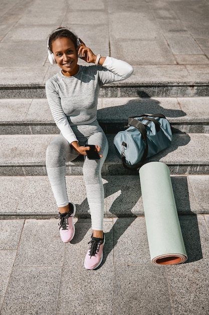 Woman in sportswear sitting on the stairs waiting for fitness workout