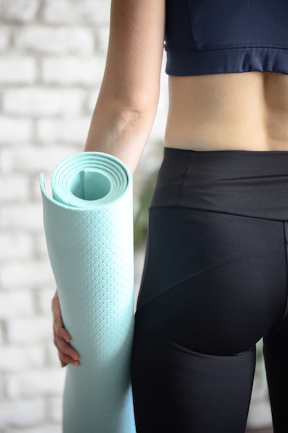 Woman in sportswear with sports equipment and holding thermos bottle after a workout in the gym. Sport and healthy lifestyle concept.