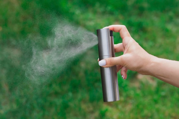 Woman sprays liquid from a steel bottle