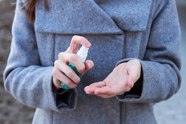 Woman sprays sanitizer to disinfect hands