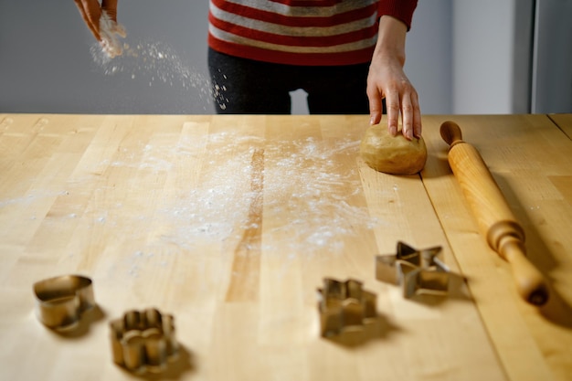 Woman sprinkles flour on table to roll out dough