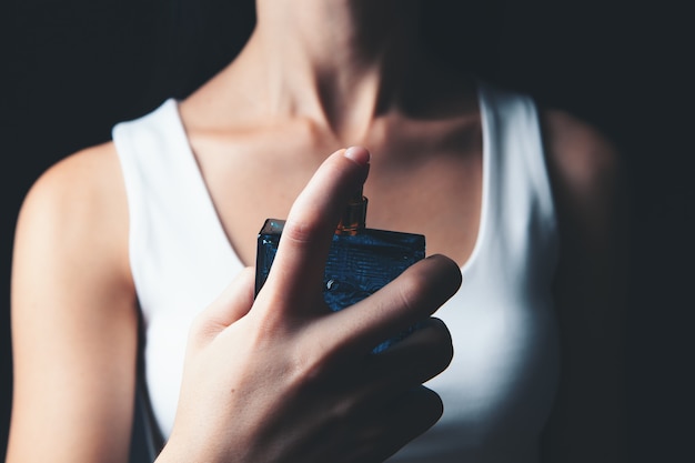 Woman sprinkles perfume on her neck