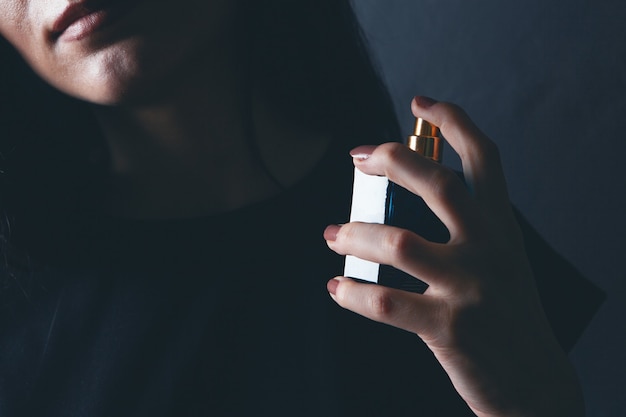 Woman sprinkles perfume on her neck