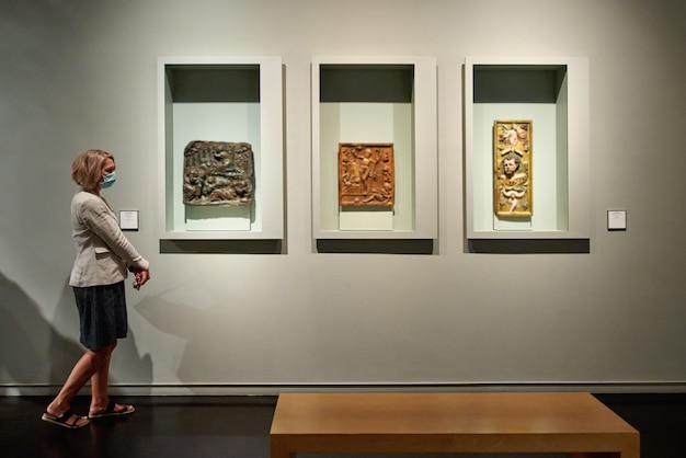 Woman stading in a room looking and pointing at the empty frames displayed