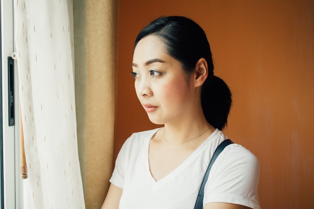 Woman stand by the window with soft warm light.