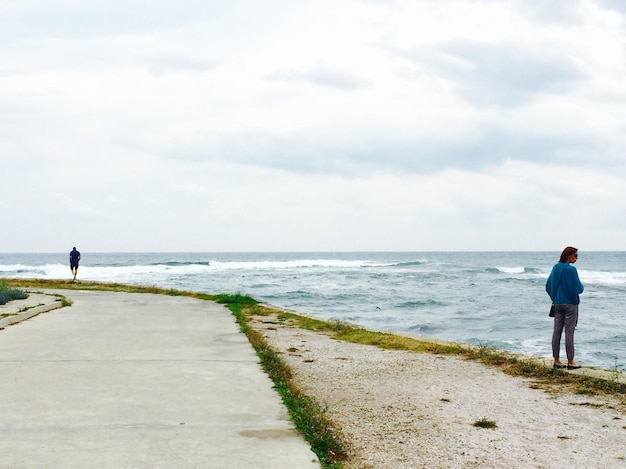 Photo woman standing at beach against sky