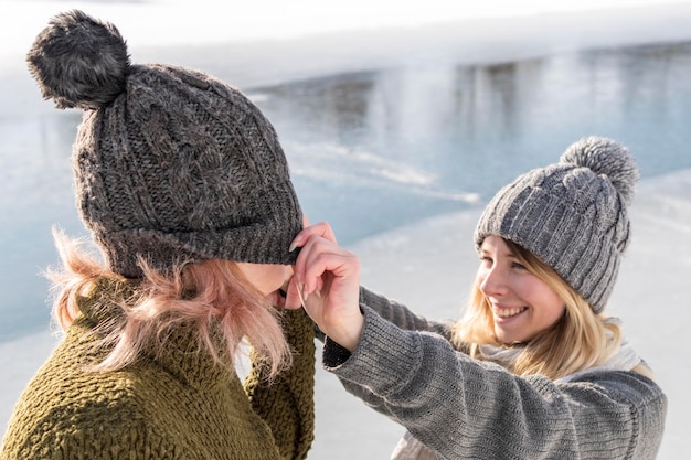 woman standing by the river, pulled a hat on the nose of her friend