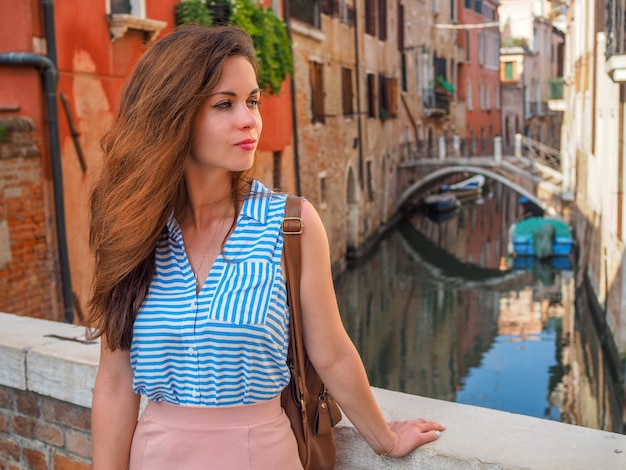 Woman standing over a canal while sightseeing in a Venice, Italy