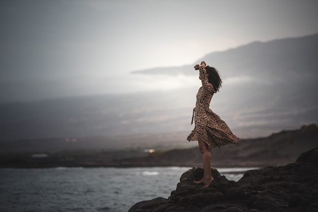 Woman standing in a cliff seashore with the ocean below