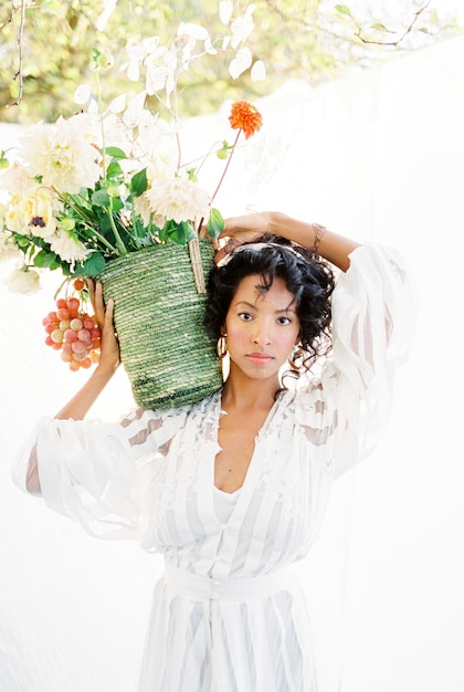 Woman standing in the garden with a basket of flowers on her shoulder