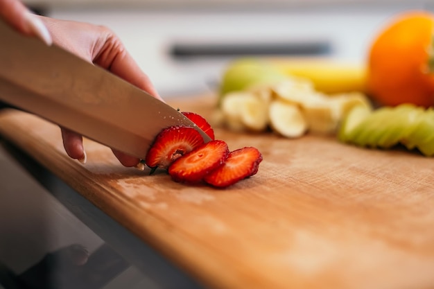 Woman standing in the kitchen and chopping salad with healthy food