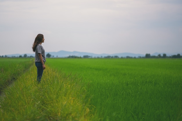 A woman standing and looking at a beautiful rice field with feeling relaxed and calm