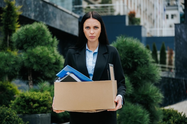 A woman standing outside holding a box looking lost and jobless an unemployed woman with a lost job