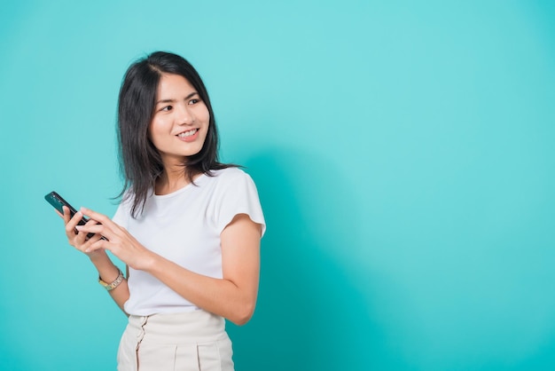 Woman standing smile holding mobile phone looking back to space