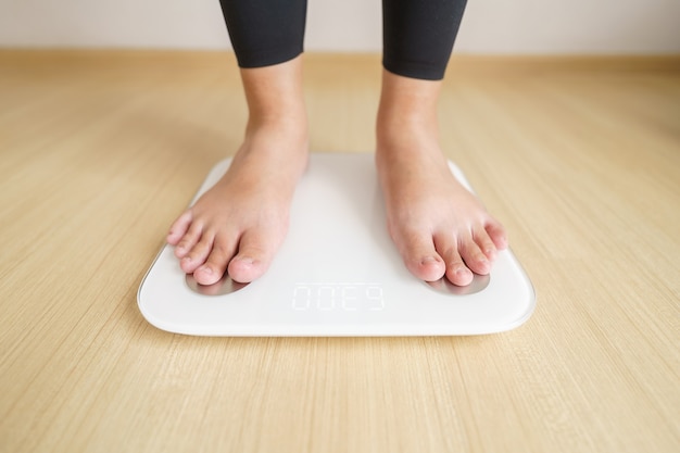 Woman standing on weigh electronic scalesfor check weight. diet lifestyle concept to reduce