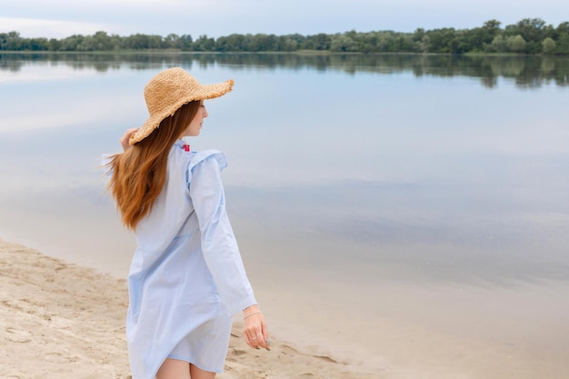 Woman standing with back in a straw hat in the summer