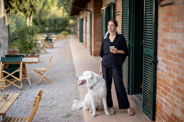 Woman standing with dog and looking away near entrance to hotel room