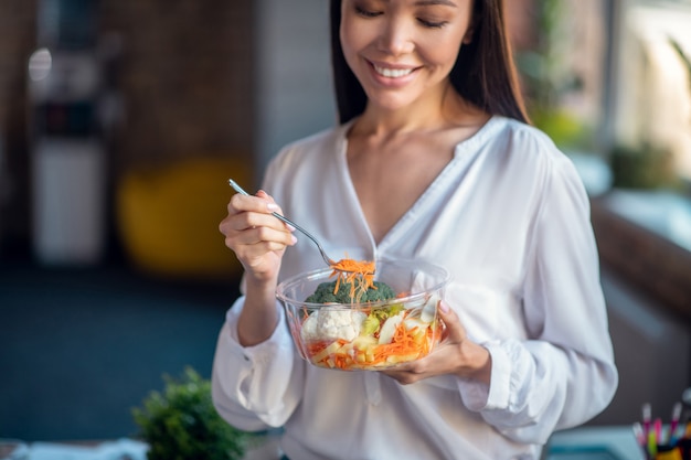 Woman standing with her salad while having lunch