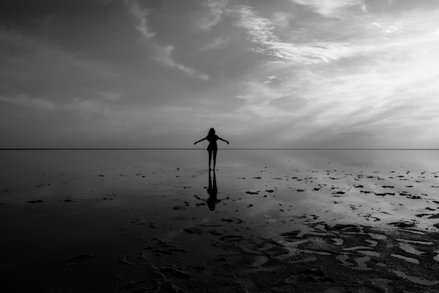 Photo a woman stands on a beach with her arms outstretched.