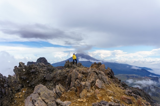 Woman stands on the edge of a cliff with a beautiful sky with the background popocatepetl volcano