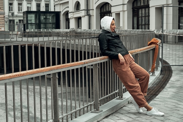 woman stands at the fence on the bridge in the city.