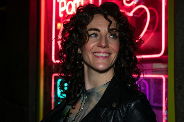 A woman stands in front of a neon sign that says'party 2'on it