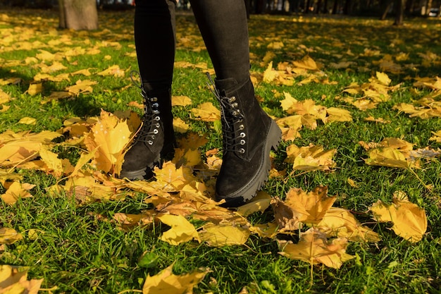 A woman stands in the grass in autumn leaves.